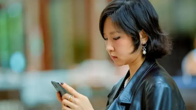یک زن چینی در حال نگاه به موبایلش