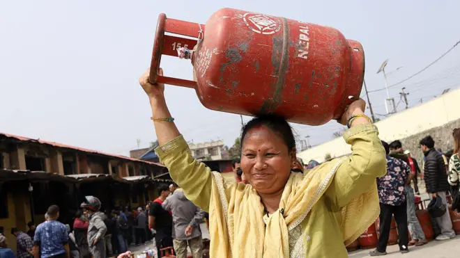 随着伊朗战争进入第二周，供应中断，国家垄断企业尼泊尔石油公司（NOC）开始实施液化石油气（LPG）即厨用瓦斯的配给制度，以应对需求激增。根据尼泊尔石油公司的命令，装瓶厂开始向顾客销售半满的瓦斯罐，迫使人们排长队等候数小时。根据新规定，无论是家庭用户还是旅馆餐厅用户，都将获得 7.1 公斤的瓦斯罐，容量是通常的一半。这家国家垄断企业声称，尽管进口未受影响，此举旨在节约能源。一个 7.1 公斤的厨用瓦斯罐售价为 955 尼泊尔卢比。尼泊尔石油公司的这项决定距上一次实施已间隔 5 年。尼泊尔石油公司在 2015 年和 2020 年的先前危机期间也曾采取类似措施，当时该国遭遇了严重的厨用瓦斯短缺。这家燃料垄断企业表示，来自印度的供应保持正常，但加德满都谷地的抢购现象愈演愈烈。中东地区是全球市场的主要燃料供应地区，随着该地区地缘政治紧张局势升级，当地杂货店无法在整个谷地供应燃料后，厨用瓦斯仓库前的队伍越来越长。