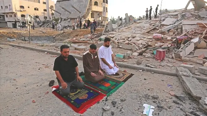Qəzza zolağının şimalında İsrailin hava hücumlarından sonra dağıdılmış binalar arasında bayram namazını qılan müsəlmanlar. Bayram günlərinə rəğmən zorakılıq səngimək bilmir. Son məlumata görə, qarşıdurma Qəzzada ən azı 83, İsraildə isə yeddi nəfərin ölümünə səbəb olub