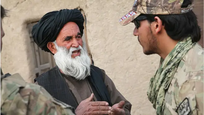 An Afghan interpreter with the US Army seen speaking with a villager