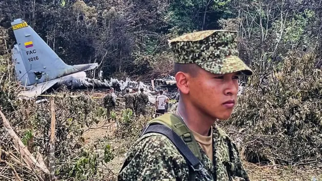 Un soldado joven, con gesto serio, en el lugar donde cayó el Hércules C-130 de la Fuerza Aérea de Colombia. En el fondo se ven restos de la aeronave.