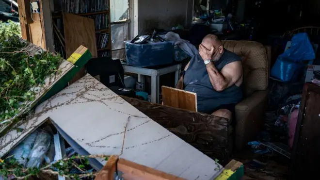 A man sits in the wreckage of his home