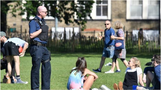 Police speak to people gathering in a park in England