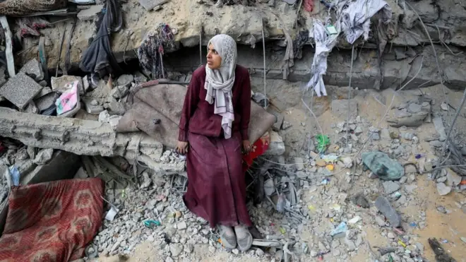 가자 지구의 건물 잔해 속에 서 있는 팔레스타인 여성