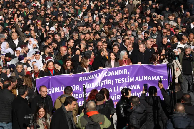 Ön tarafta DEM Parti yönetimi elinde mor bir pankart taşıyor. Arkalarında yüzlerce kişi var. Bir yürüyüşe üstten bakış. 