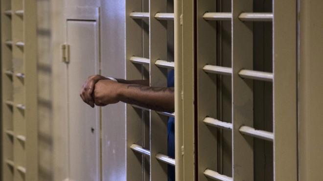 a prisoner stands in an isolation cell in the Dane County Jail in Madison, Wis.