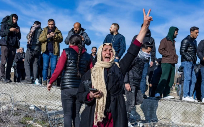 Zafer işareti yapan başörtülü bir kadın slogan atıyor, arkasında en az 10 erkek bir duvarın üzerine çıkmış duruyor. Nereye baktıklarını fotoğraftan anlayamıyoruz.