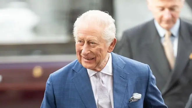 Король Чарльз у синьому костюмі і сірій краватці посміхається