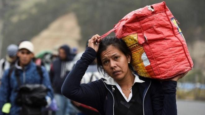 A Venezuelan woman who has emigrated carries a bag along the Pan-American highway