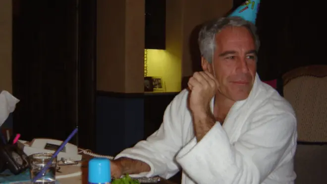 Jeffrey Epstein sat a table wearing a party hat