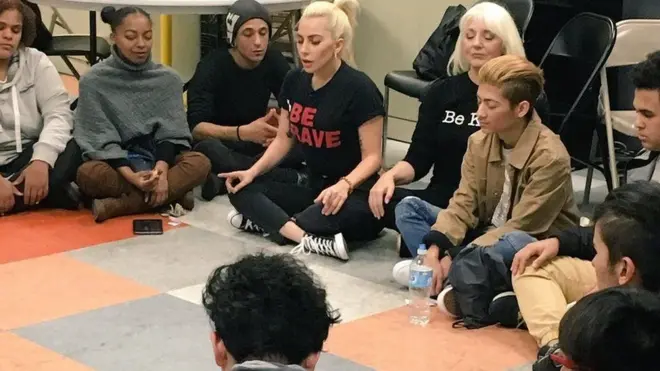 Lady Gaga (duduk di sebelah ibunya Cynthia) selama kunjungannya ke pusat penampungan tunawisma New York.