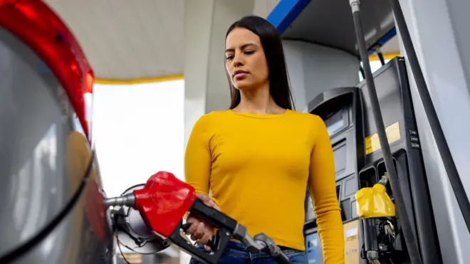Woman in yellow top fills car with petrol 