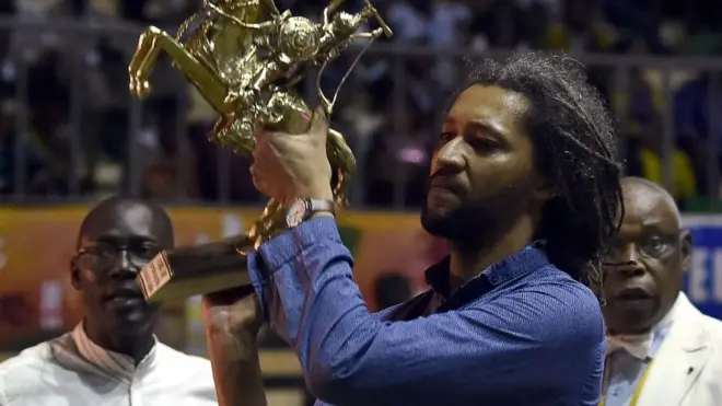 Le lauréat du 25e Festival panafricain du cinéma et de la télévision (FESPACO) Alain Gomis brandit le trophée de l'étalon de Yennega au Palais des sports de Ouagadougou, le 4 mars 2017.