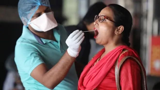 A healthcare worker collects a swab sample for covid-19 testing RT-PCR (Reverse Transcription Polymerase Chain Reaction) test from a woman at New Delhi Railway Station in Delhi.