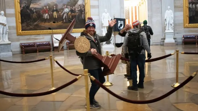 A pro-Trump protester carries the plinth of US Speaker of the House Nancy Pelosi through the Rotunda of the US Capitol Building after a pro-Trump mob stormed the building on 6 January 2021 in Washington, DC.