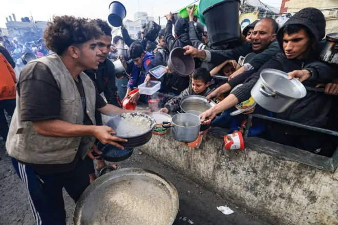 रफ़ा में बने शरणार्थी शिविर में खाना लेते फलस्तीनी