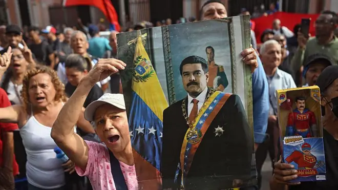 Những người biểu tình cao tuổi ở Venezuela, đội mũ và mặc quần áo sặc sỡ, cầm ảnh Tổng thống Venezuela sau khi ông bị quan đội Mỹ đưa ra khỏi nước này