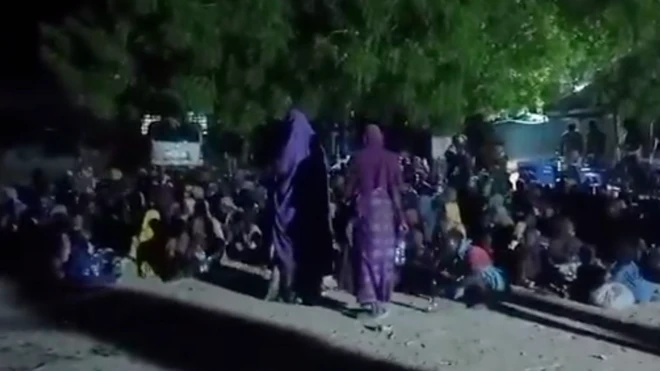 Two women wear purple wit oda children siddown for floor.
