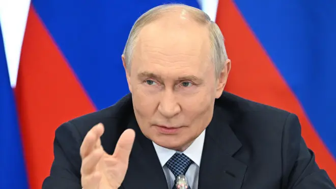 Vladimir Putin, presidente de Rusia, con traje oscuro y la bandera detrás