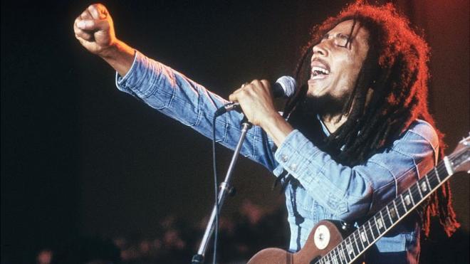 Bob Marley levantando el brazo en medio de un concierto