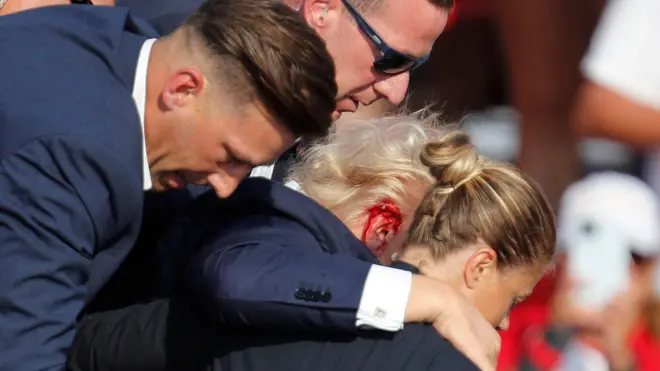 ماموران سرویس مخفی در حال خارج کردن ترامپ از محل سخنرانی بعد از سوقصد به او