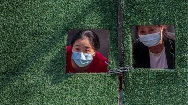 上海封城期間，因疫情被隔離的婦女透過柵欄窗朝外看