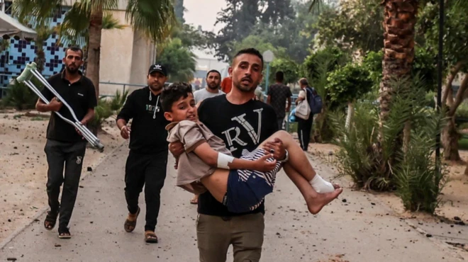 Man carrying injured child after Isareli strike in Khan Younis