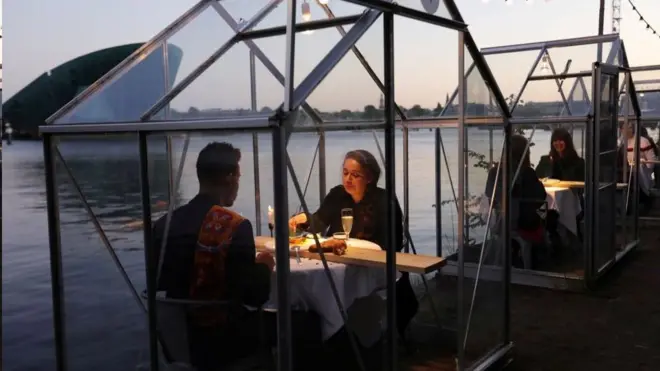 荷兰阿姆斯特丹，餐馆开门了，可以出去就餐，但要坐进“温室”。想必是别有一番滋味在心头