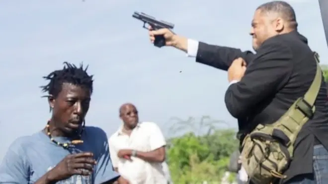 People run as Haitian senator Jean Marie Ralph Féthière holds a gun in the country's capital, Port-au-Prince