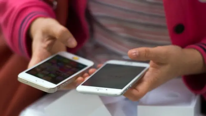 Женщина сравнивает новый айфон 6 со своим старым 5s, Шанхай, октябрь 2014 года.