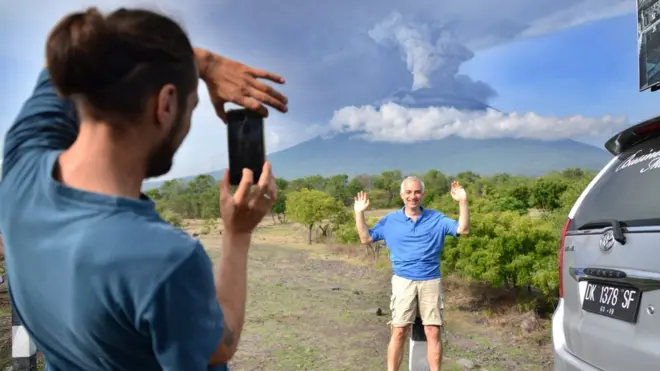 Seorang turis asing bergaya di depan kamera dengan latar belakang gunung Agung di kawasan Kubu, Kabupaten Karangasem, Bali, 27 November 2017.