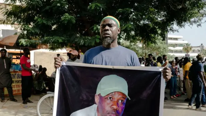 Un manifestant tient une banderole représentant l'opposant sénégalais détenu, Ousmane Sonko