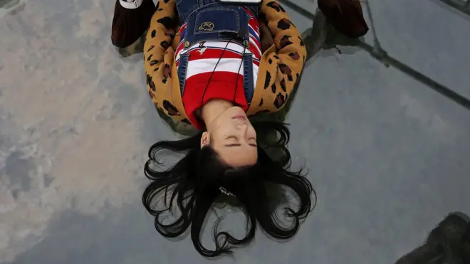 Joven china pisa en un puente de cristal.