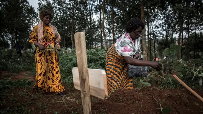 Family members place leaves on the grave of a deceased relative who died from Ebola in Butembo