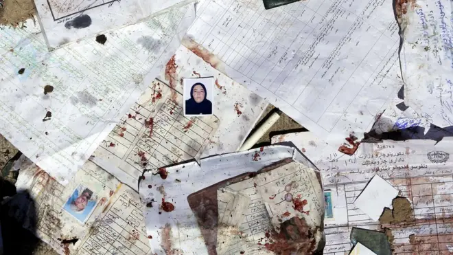 Foto calon pemilih dan formulir pendaftaran berserakan dengan tumpahan darah.