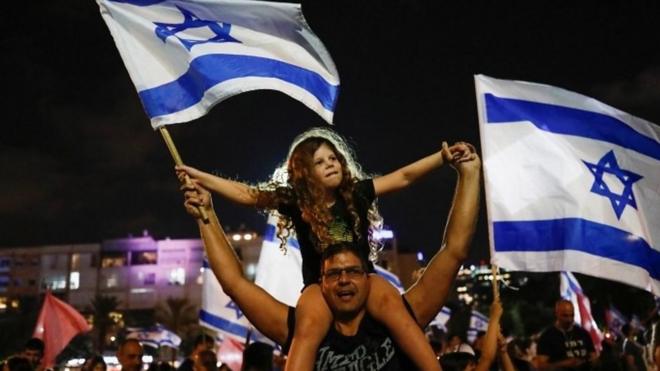 People celebrate after Israel's parliament vote in a new coalition government