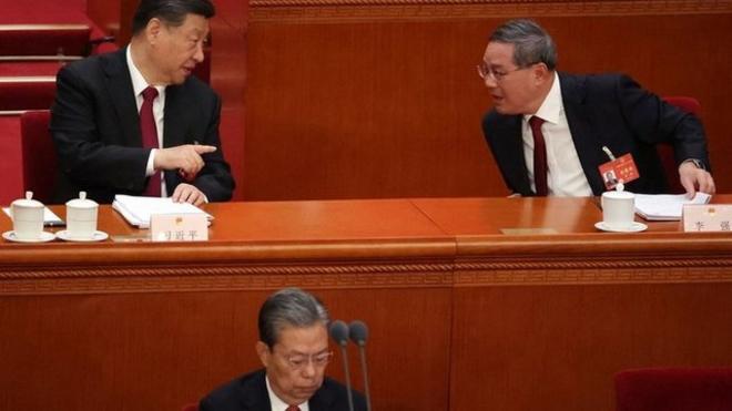 中国人大十四届二中全会开幕式上，中国国家主席习近平（后左）与国务院总理李强（后右）讲话，前面是全国人大常委会委员长赵乐际。