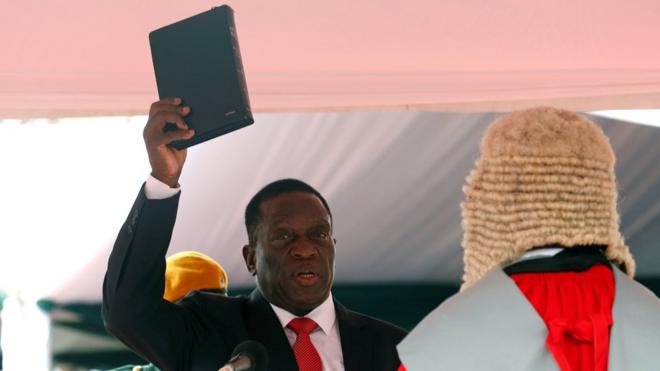 Emmerson Mnangagwa holding up a Bible while being sworn in