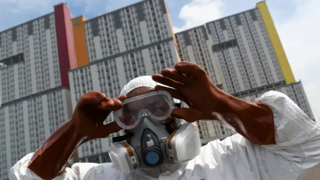 Petugas Palang Merah Indonesia (PMI) memakai kacamata pelindung untuk melakukan penyemprotan cairan disinfektan pada Wisma Atlet di Kemayoran, Jakarta, Sabtu (21/03)