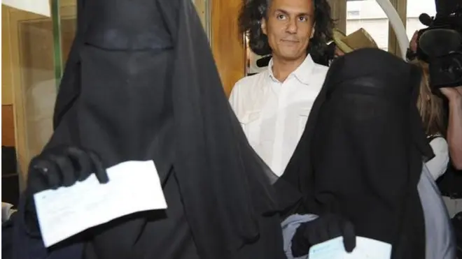 Dua perempuan menunjukkan denda yang harus dibayar karena menggunakan penutup wajah secara penuh di Brussels pada 2011. Pembayaran denda mereka ditanggung oleh pengusaha Prancis, Rachid Nekkaz (tengah).