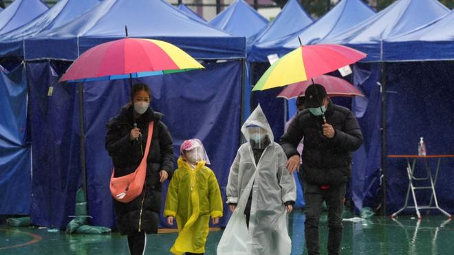 People walk in the rain in front of tents at a testing site for the coronavirus disease (COVID-19) in Hong Kong, China February 22, 2022