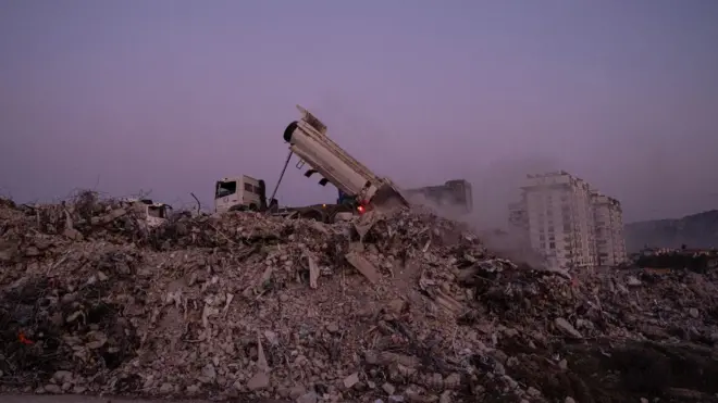 самосвал на руинах дома