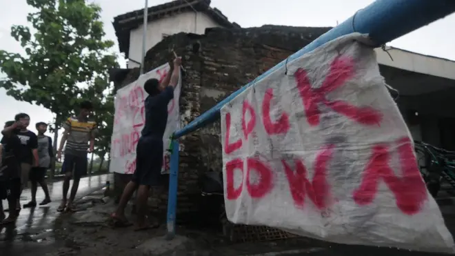 Warga memasang spanduk pada portal karantina wilayah di Bendosari, Sawit, Boyolali, Jawa Tengah, Selasa (31/03).