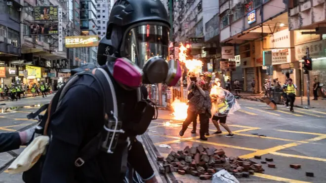 在湾仔，一名现场工作的传媒工作人员（画面后方）被汽油弹击中。