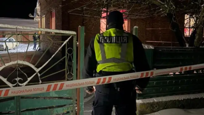 Поліцейський стоїть біля обмежувальної стрічки, на вулиці ніч