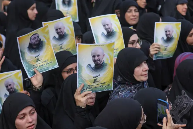 ผู้หญิงถือรูปถ่ายของสมาชิกกลุ่มฮิซบอลเลาะห์ อาลี ฟตูนี และ ฮุสซัม อิบราฮิม ซึ่งเสียชีวิตระหว่างการยิงปืนใหญ่ของอิสราเอลทางตอนใต้ของเลบานอน โดยงานศพของทั้งคู่จัดขึ้นในคิร์บิต ซิลม์ ทางตอนใต้ของเลบานอน เมื่อ 10 ต.ค.