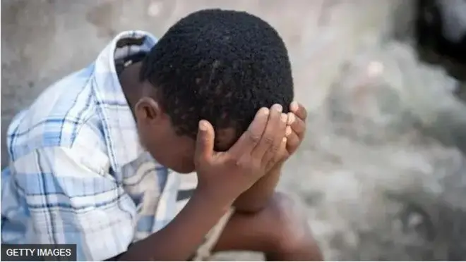 Ọmọde kan joko dorikodo o wa ka ọwọ sori.