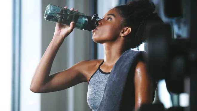 Woman wey dey drink from water bottle