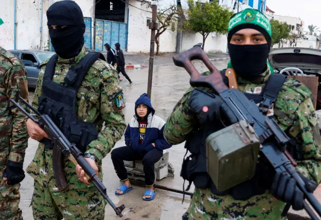 يقف مسلحون من حركة حماس الفلسطينية حراسًا بينما يتجمع الناس في يوم تسليم الرهائن، بمن فيهم أولئك المحتجزون في غزة منذ الهجوم المميت في 7 أكتوبر 2023، إلى أعضاء اللجنة الدولية للصليب الأحمر كجزء من وقف إطلاق النار وصفقة تبادل الأسرى بين حماس وإسرائيل، في رفح في جنوب قطاع غزة، 22 فبراير 2025.