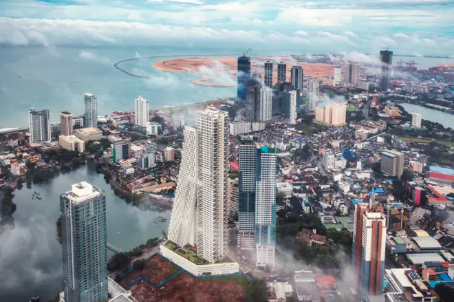 Drone photo of the beautiful sunrise view above the clouds in the downtown district and Port City of Colombo city, Sri Lanka Port City is also called Colombo International Financial City which is a special economic zone and International Financial Centre located in Colombo, Sri Lanka, it is currently under construction on reclaimed land adjacent to the Galle Face Green. The project is part of China's Belt and Road initiative. Colombo is the commercial capital and largest city of Sri Lanka. According to the Brookings Institution, Colombo metropolitan area has a population of 5.6 million Photo taken on 25/11/2021